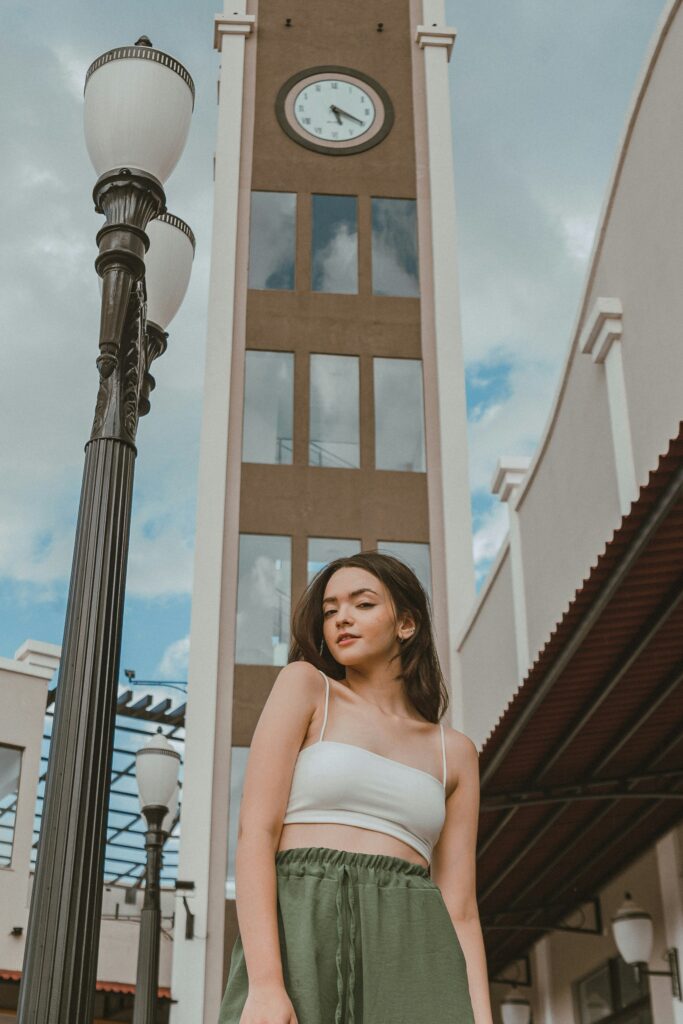 a woman standing next to a tall clock tower