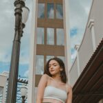 a woman standing next to a tall clock tower